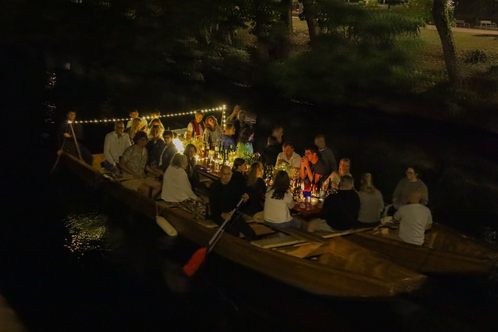Die volle Tafel an Bord bei Laternen- und Lichterkettenlicht mit Wein und Gästen